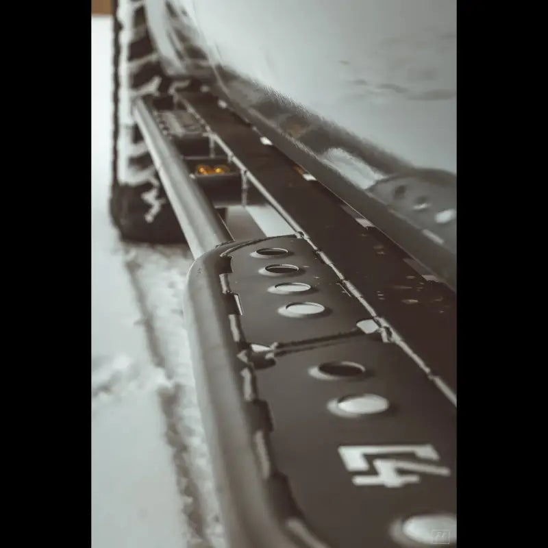 Detailed close-up of Tundra 2nd Gen rock sliders in snow, showcasing step plate and bolt-on installation design.