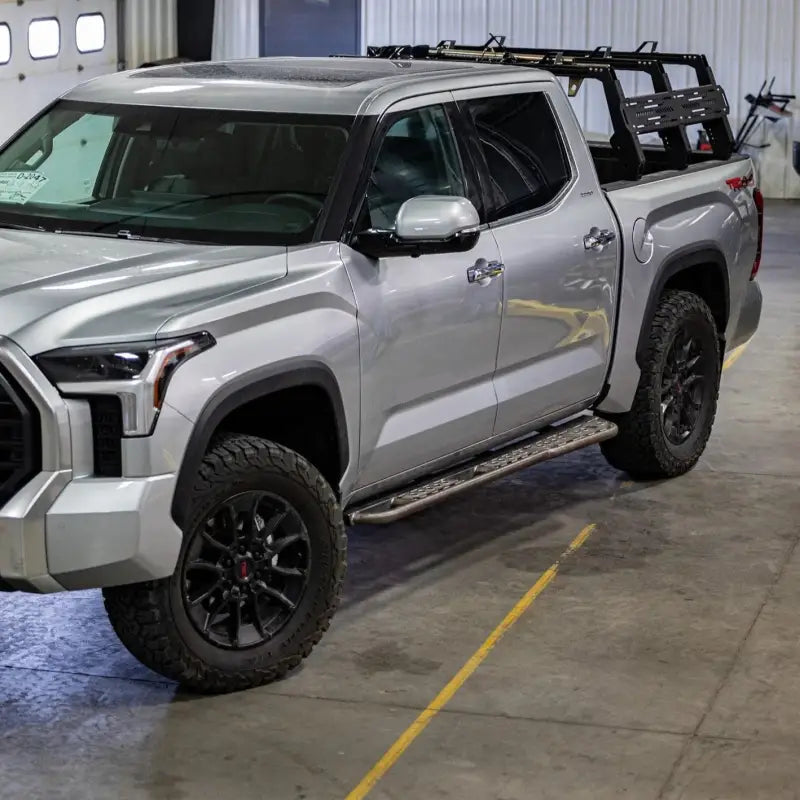 Silver 3rd Gen Tundra 2022+ truck with bolt-on rock sliders and DOM tubing, parked in a garage with rugged tires.