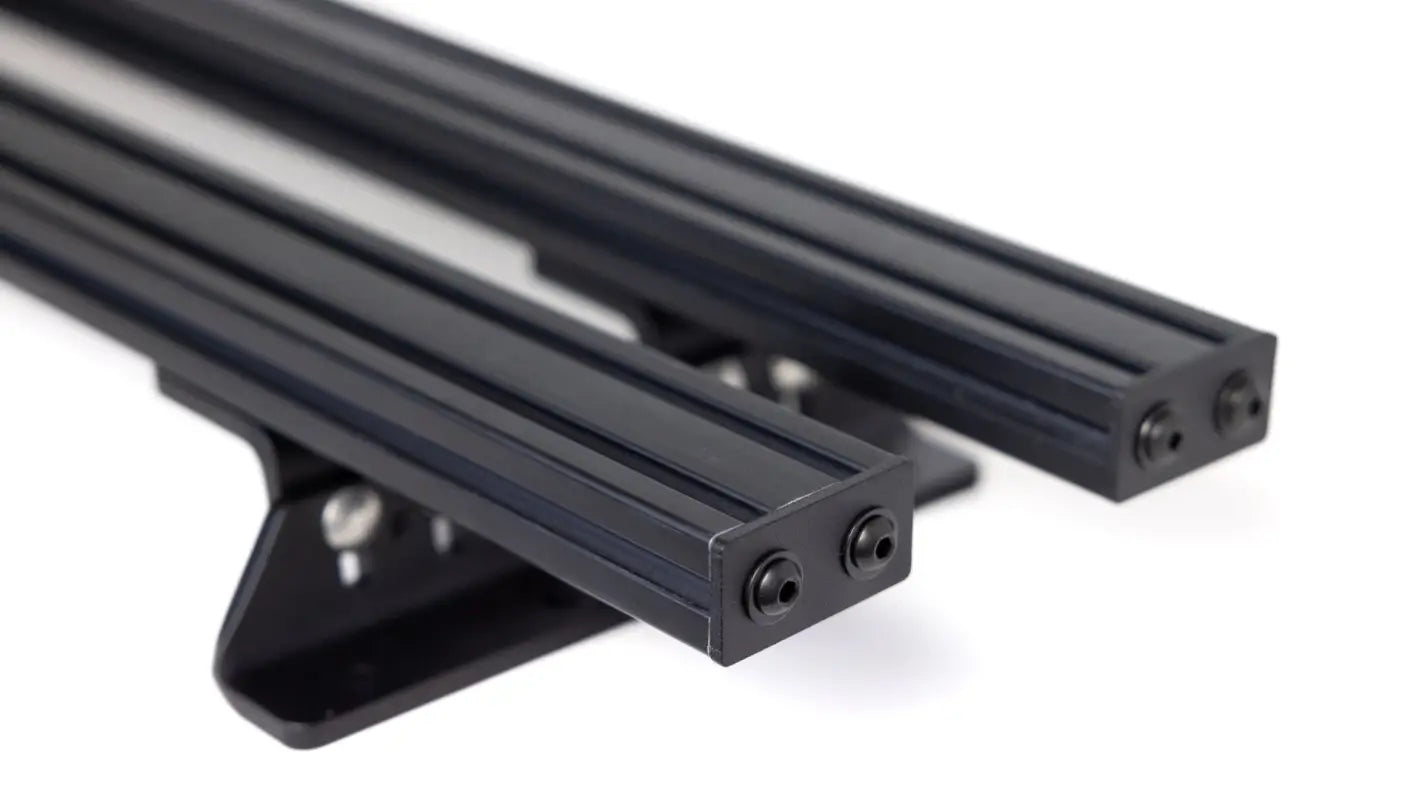 Pair of black aluminum Roof Track Load Bars with mounting feet, designed for universal compatibility with M6/M8 track nuts.