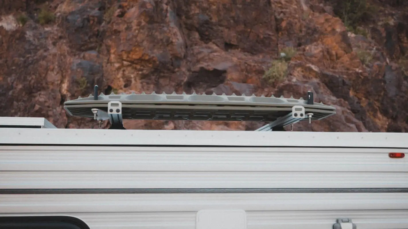 Side view of a camper with Roof Track Load Bars mounted, carrying recovery boards, ideal for off-road and camping gear storage.