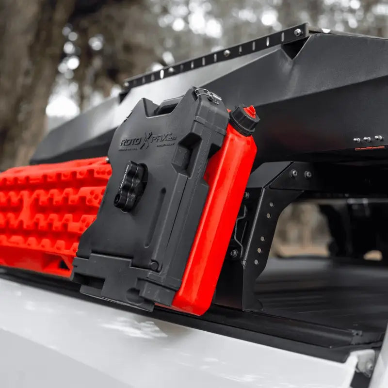 Shiprock Mid Height Rack equipped with red Rotopax fuel container and recovery boards, mounted on a T-slot rail system for off-road utility.
