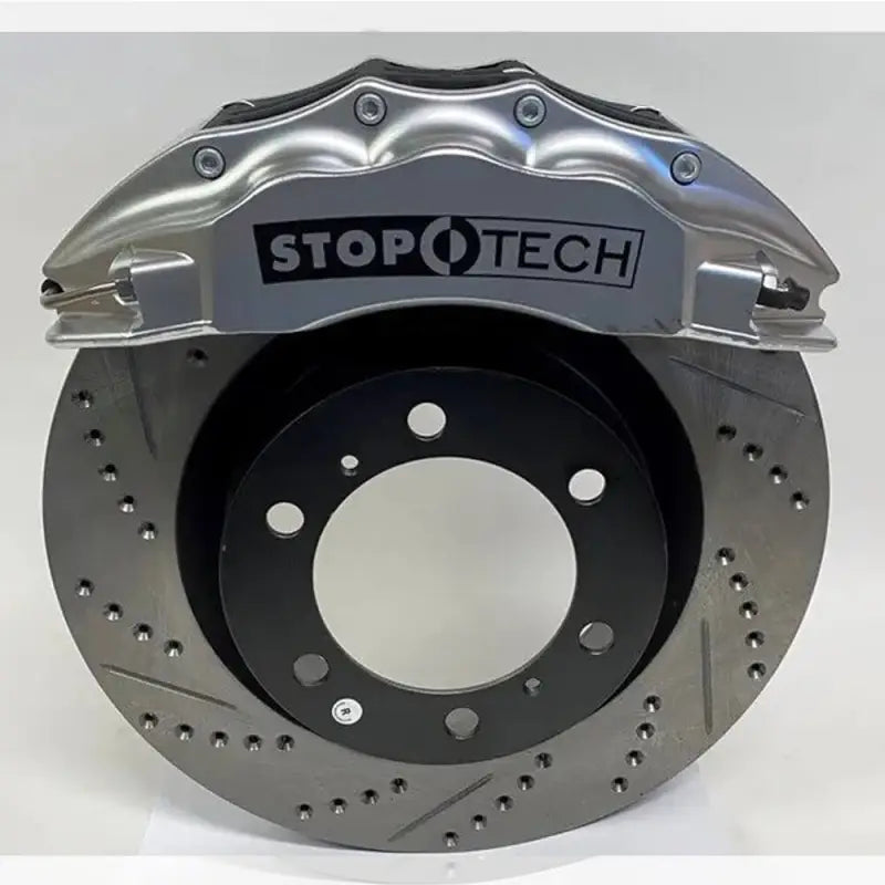Silver StopTech 6-piston caliper with drilled rotor for Toyota Tacoma, engineered for high-performance braking.