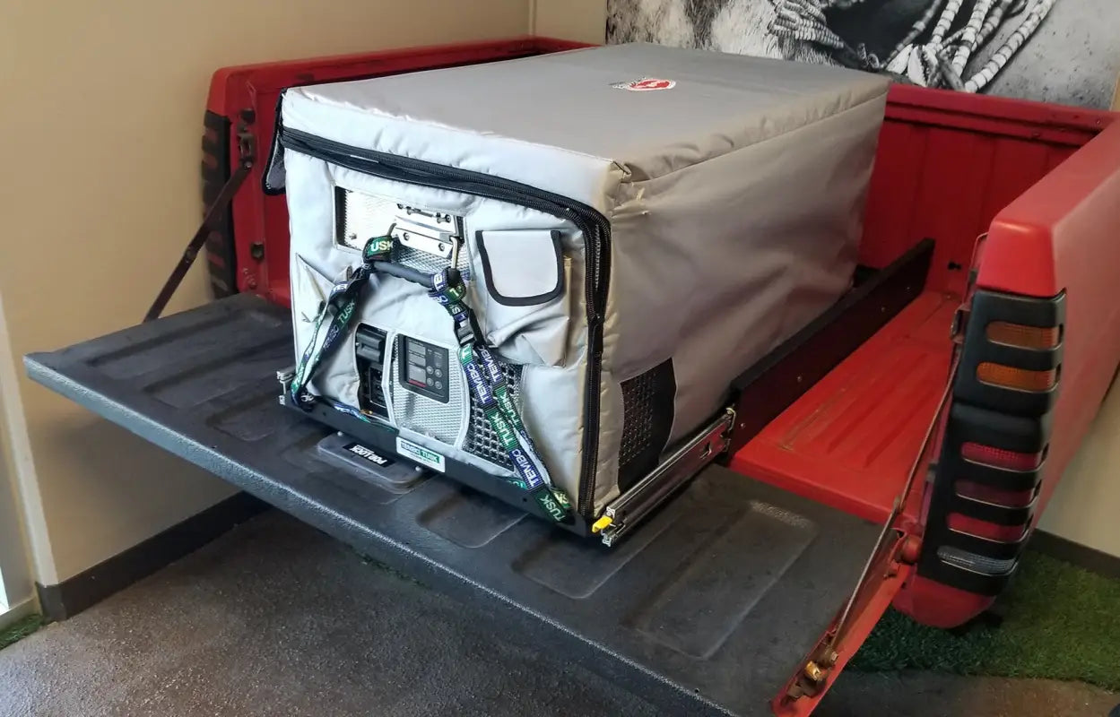 Heavy-duty SUPER Jumbo Side Pull Slide installed in a truck bed, securely holding a large fridge with protective cover for overland trips.