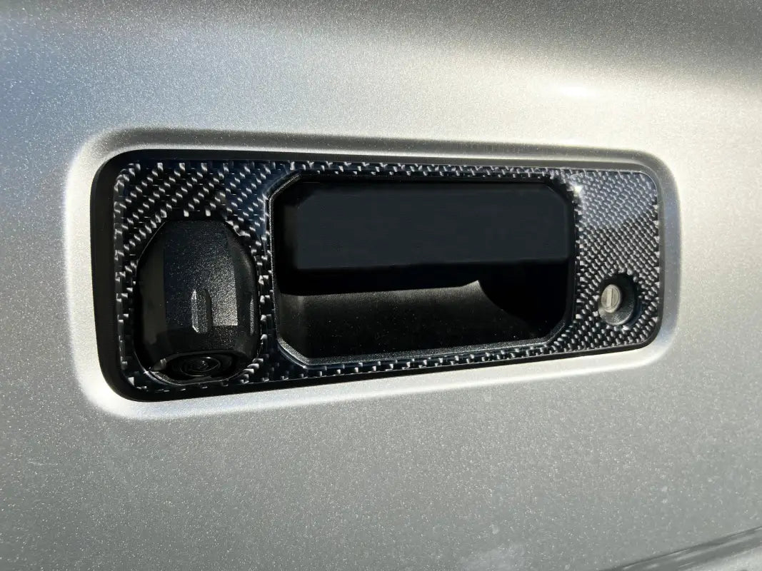 Close-up of a carbon fiber tailgate handle accent overlay on a 2016-2023 Toyota Tacoma, showcasing its durable and stylish finish.