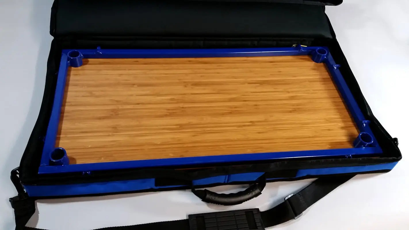 TemboTusk Camp Table Kit bamboo top stored in a blue carrying case with shoulder strap. Lightweight and travel-friendly.