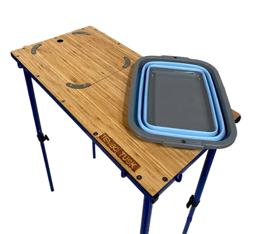 TemboTusk Camp Table featuring a collapsible blue basin and bamboo surface with a removable cover. Compact and portable design.