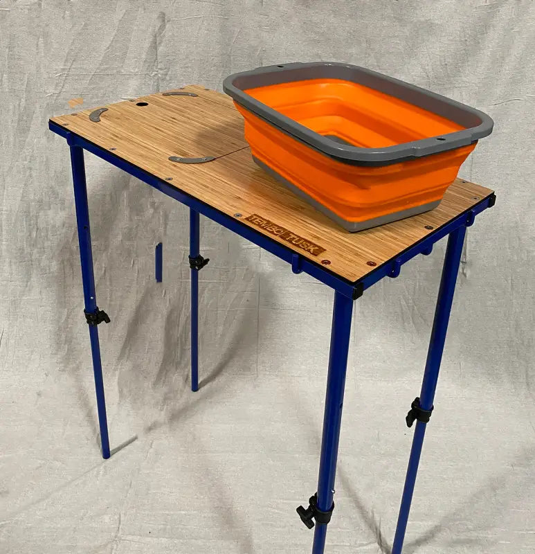TemboTusk Camp Table with collapsible orange basin on bamboo top and adjustable legs. Ideal for camping and hiking.