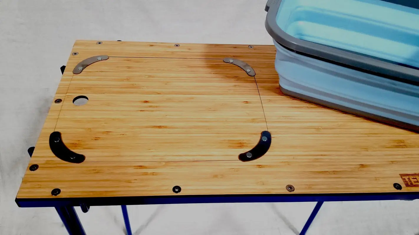 Close-up of TemboTusk Camp Table bamboo surface with integrated slots for collapsible basin. Durable and functional for camping.