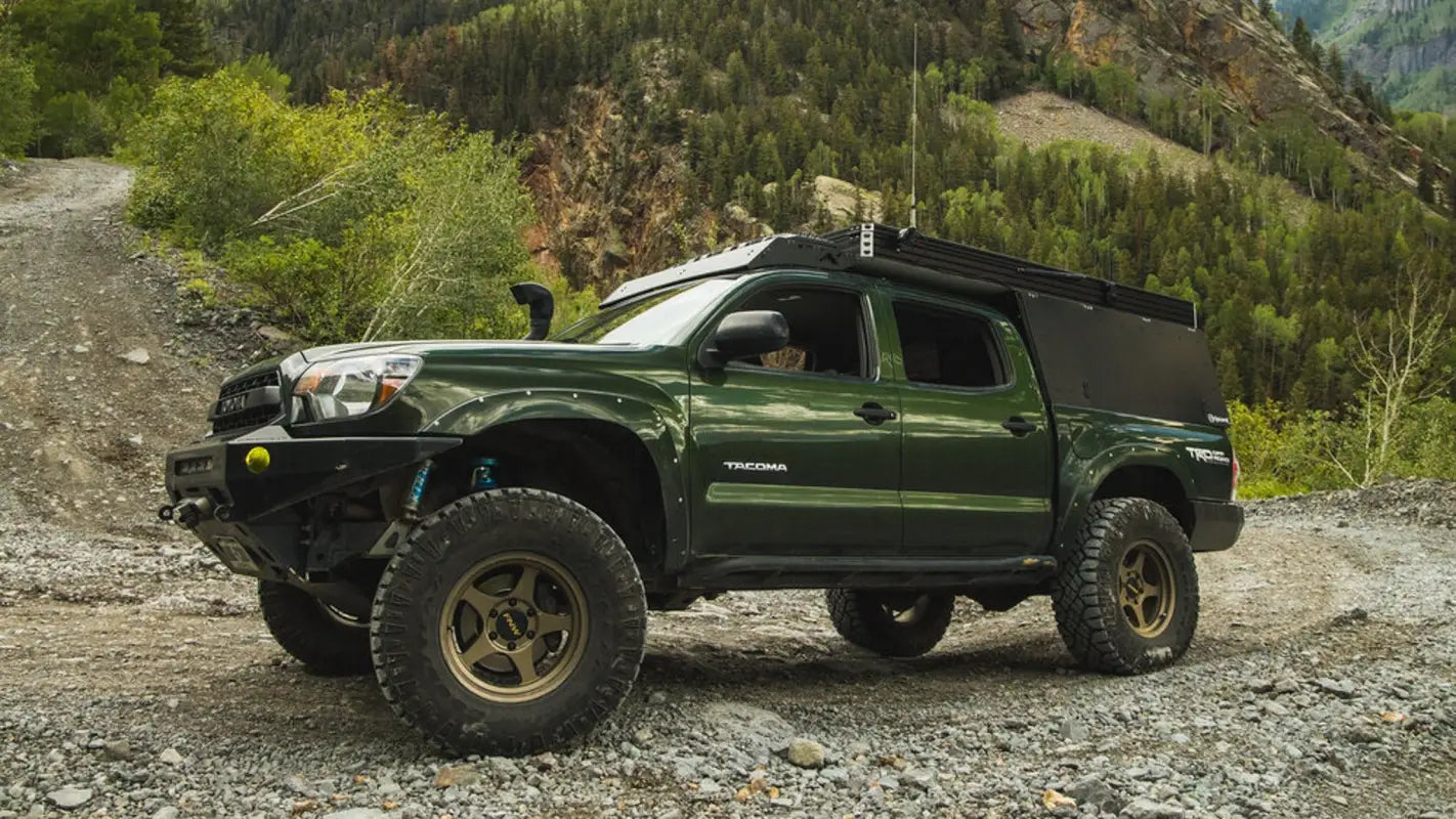 Toyota Tacoma with Animas roof rack in a rugged mountain setting, ideal for carrying extra gear or solar panels.