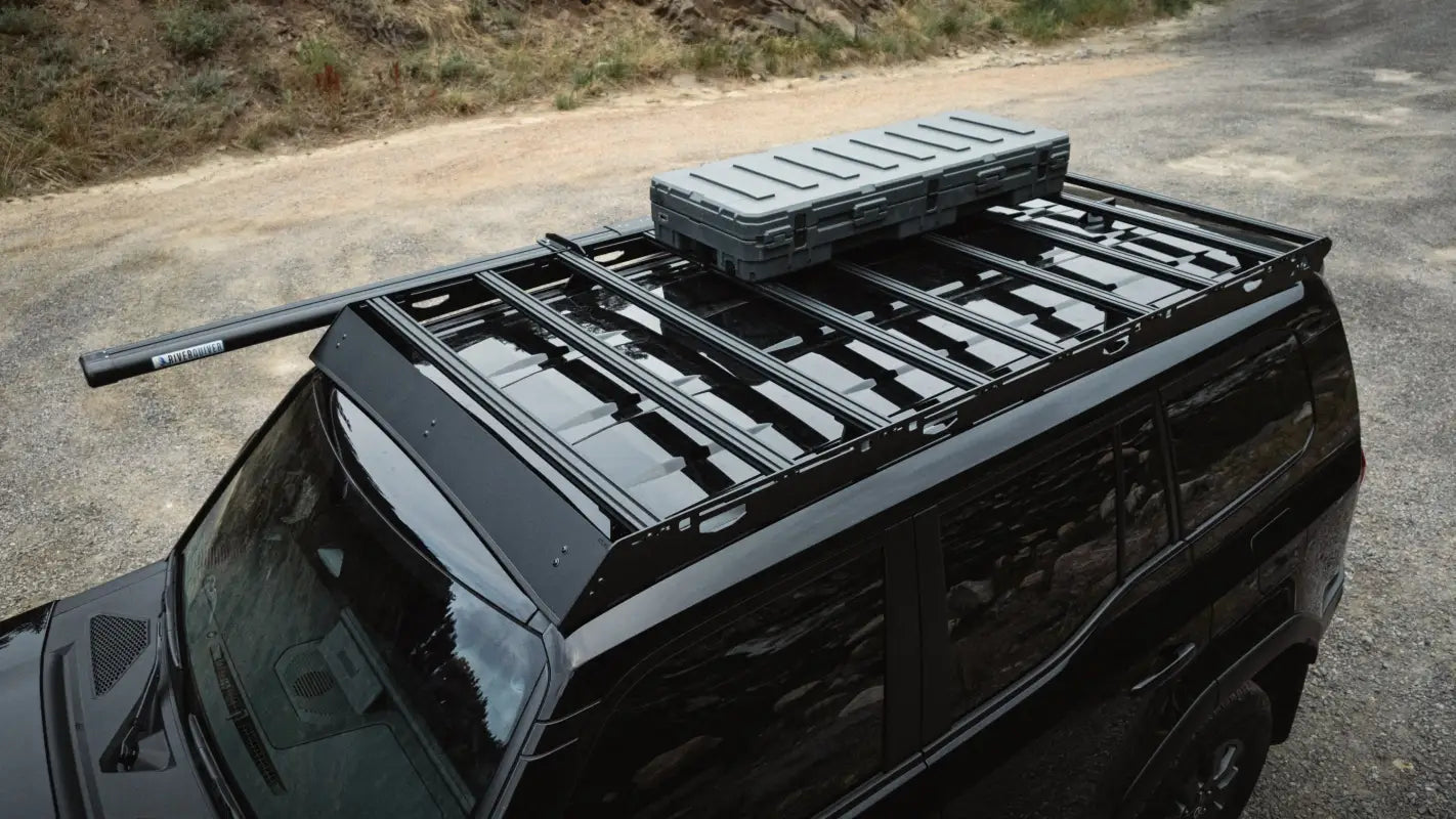 Angled top view of The Atlas roof rack on a black 2024 Toyota Land Cruiser, showcasing its full-length design and mounted gear.