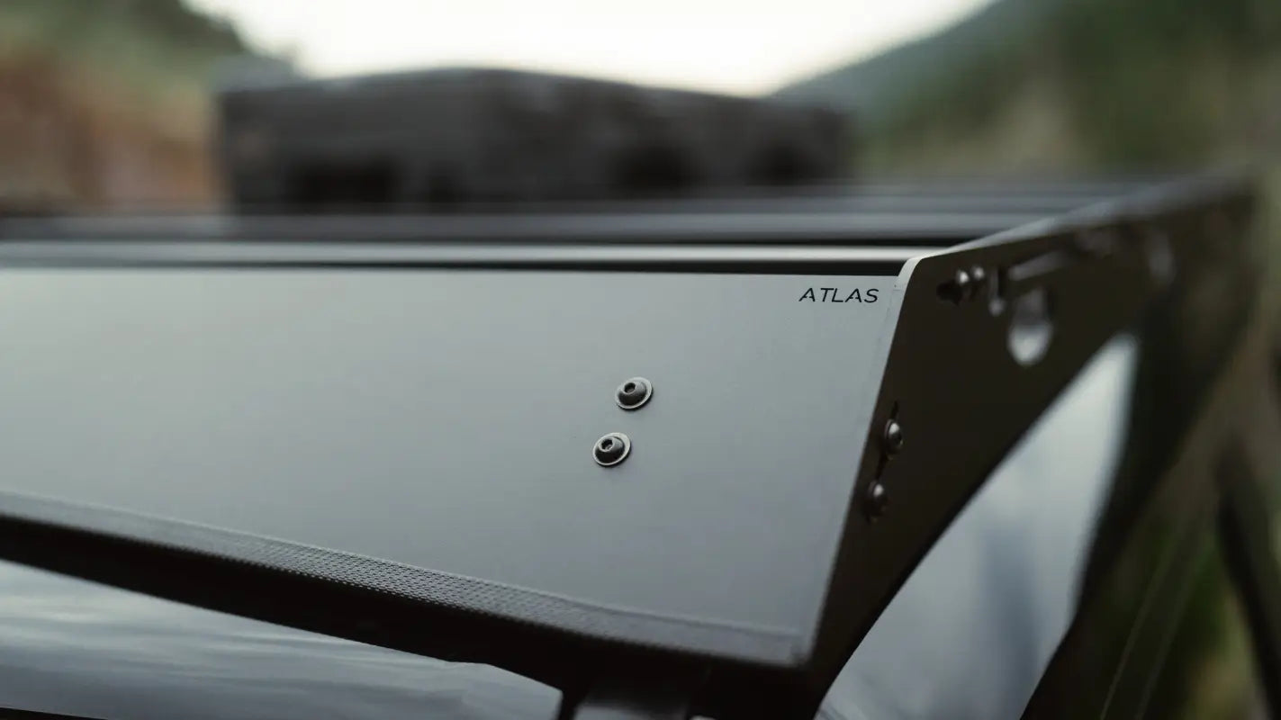 Close-up of The Atlas branding on the roof rack, highlighting its durable black aluminum finish and rugged design.