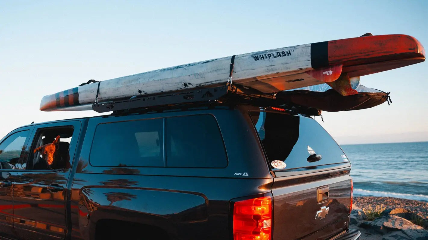 Black truck with the Crow’s Nest roof rack carrying a kayak, ideal for outdoor adventures and gear transportation.