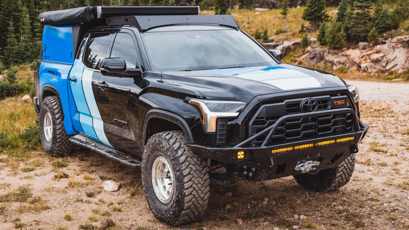 Front angle of a Toyota Tundra with The Cub Roof Rack, camper setup, and off-road bumper, designed for outdoor adventures.
