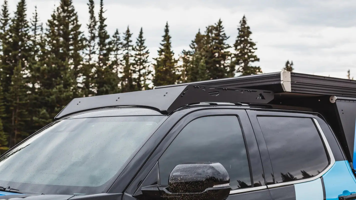 Front section of The Cub Roof Rack on a Toyota Tundra, featuring a sleek black fairing and robust design for camper storage.