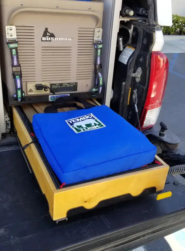 TemboTusk Fire Pit stored in a blue carry bag, neatly placed in a vehicle drawer system, emphasizing its portability and compact design.