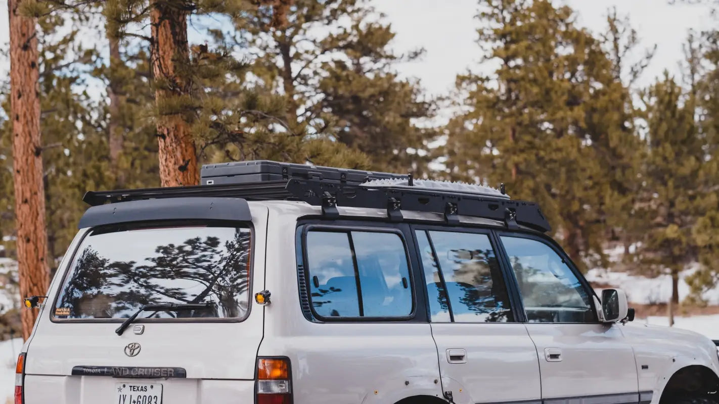 Rear view of the La Sal roof rack on an 80 Series Land Cruiser, carrying storage boxes in a snowy forest environment.