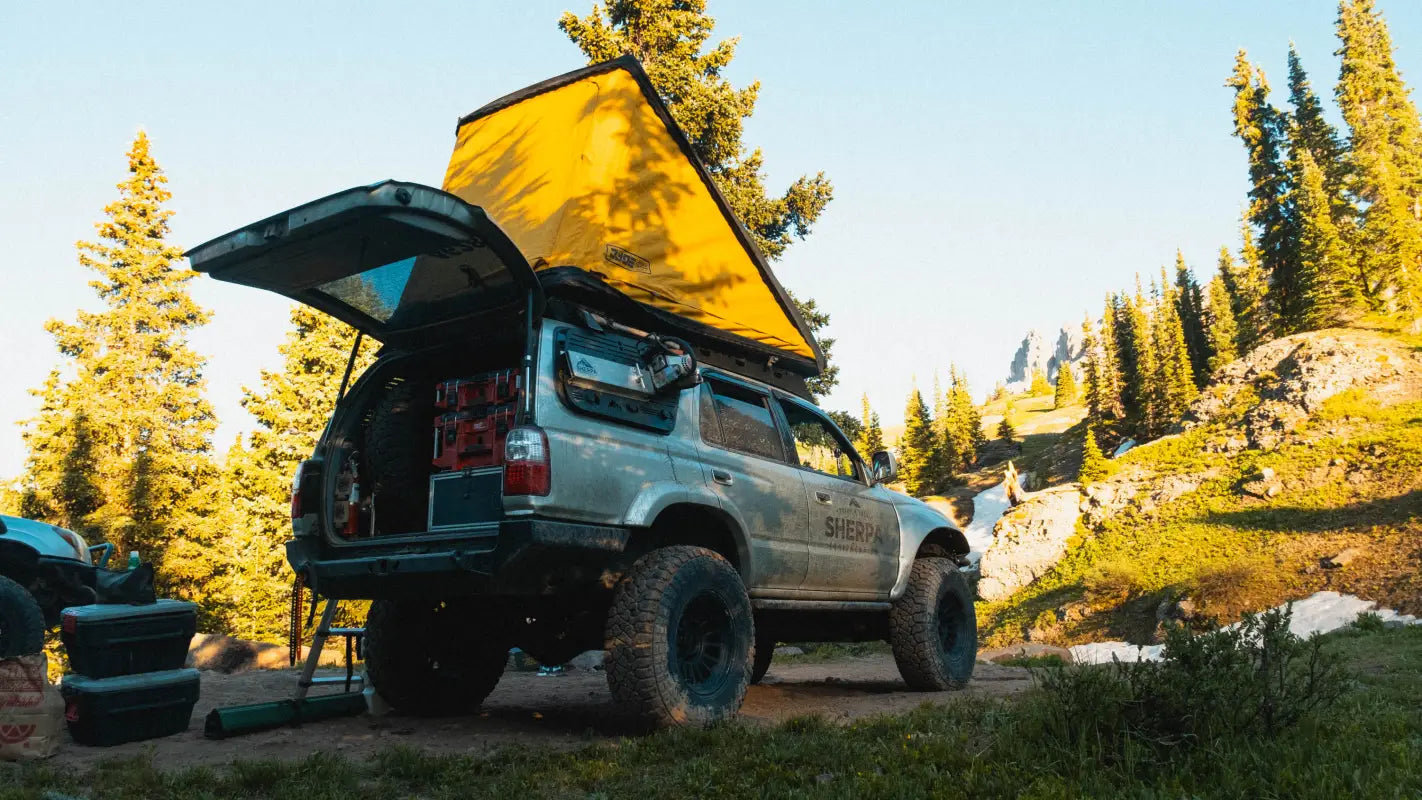 Toyota 4Runner with Matterhorn roof rack and rooftop tent, set up for camping in a mountainous forest area.