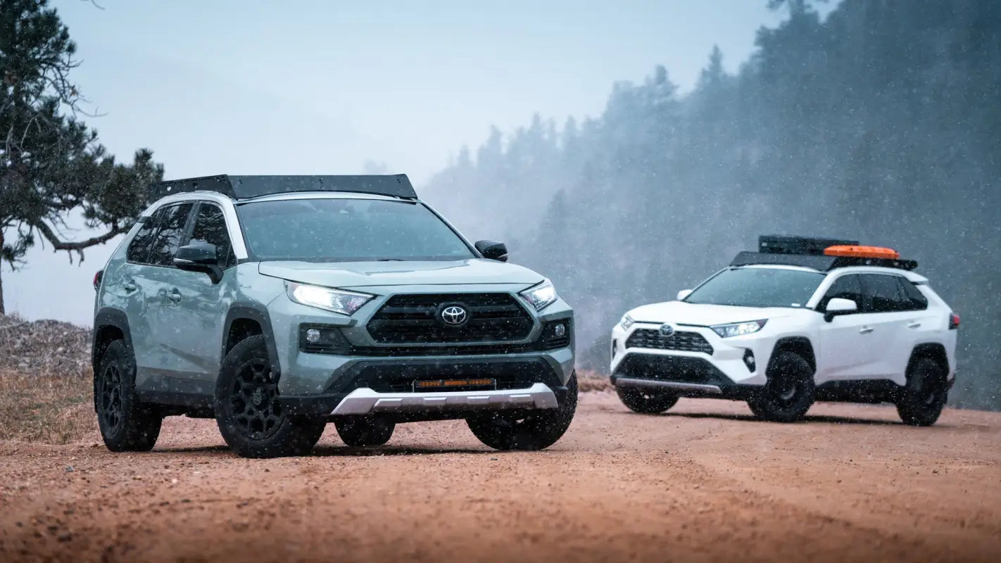Gray and white RAV4s with The Snowmass roof racks driving through snowy terrain, emphasizing durability and outdoor readiness.
