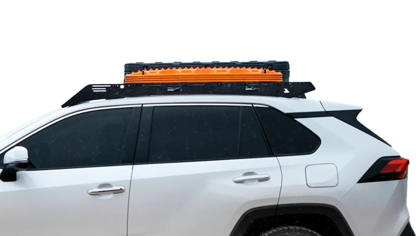 Close-up side view of The Snowmass roof rack on a white RAV4, showcasing its black aluminum design with mounted orange recovery boards.