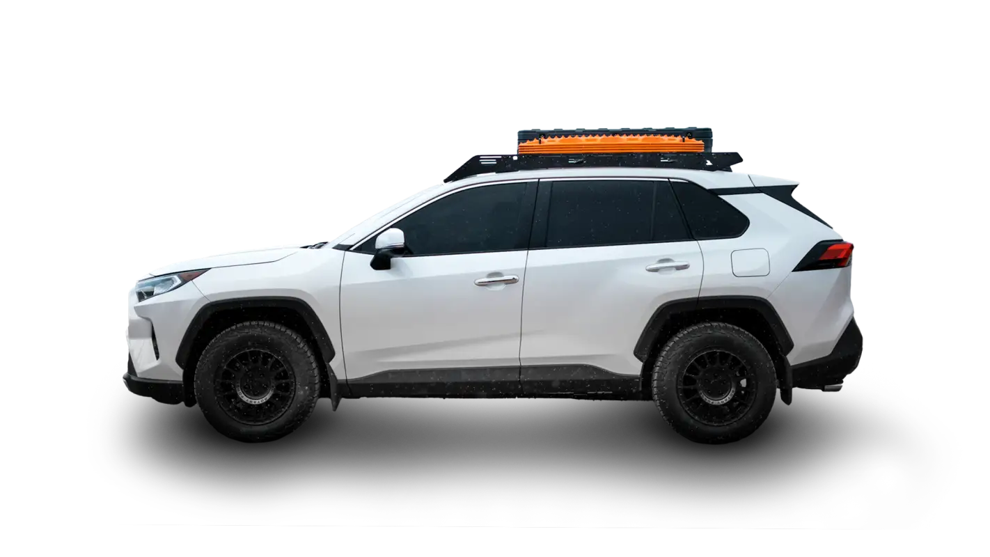 White 2019-2024 Toyota RAV4 equipped with The Snowmass roof rack in black finish, carrying orange recovery boards and a storage box.