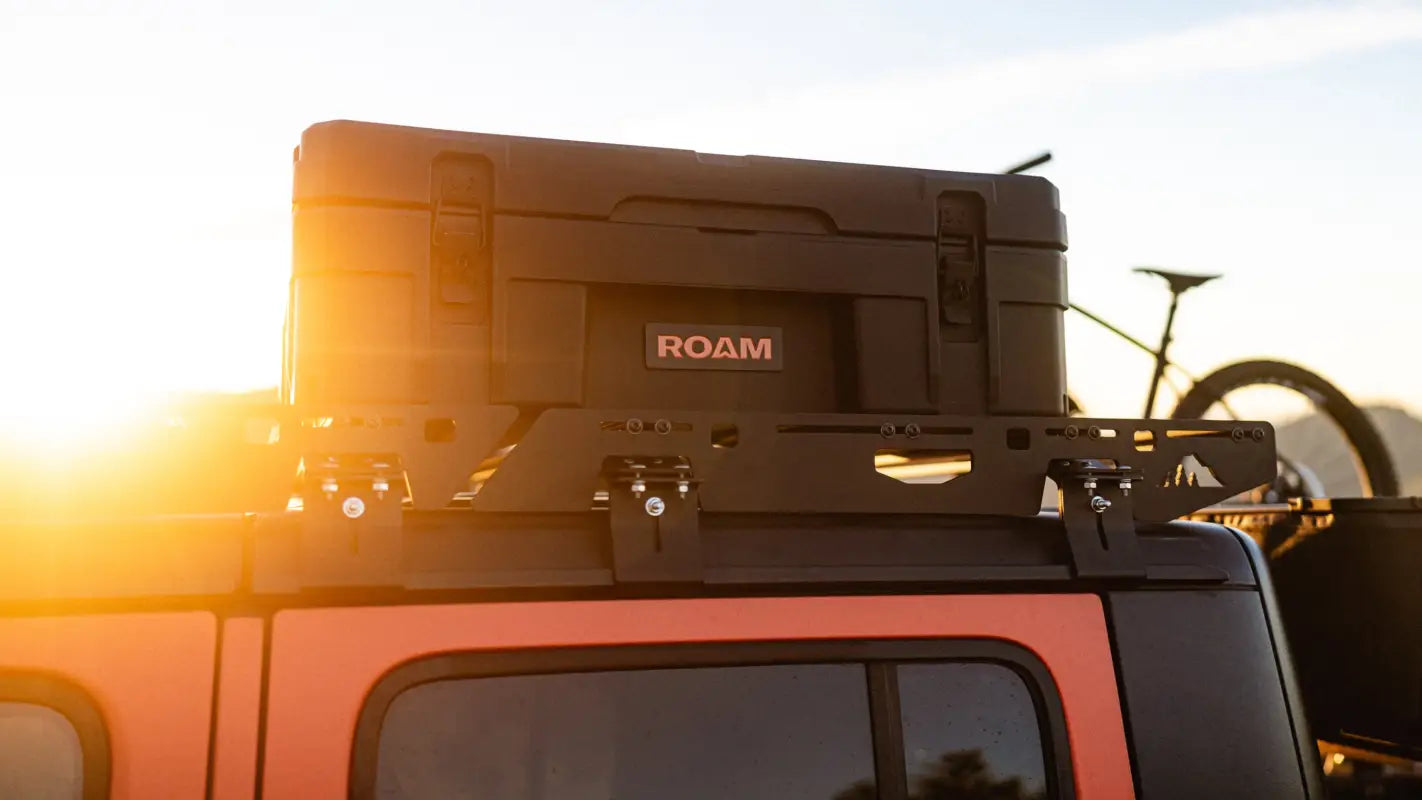 Close-up of The Sunlight roof rack on Jeep Gladiator JT, featuring a ROAM storage box and modular mounting system at sunset.