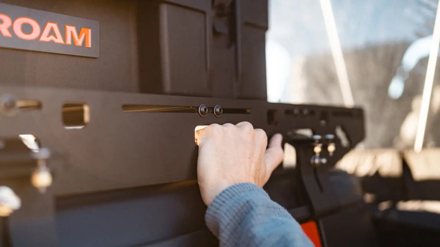 Hand gripping The Sunlight roof rack's side bracket on Jeep Gladiator JT, demonstrating its ergonomic and sturdy design.