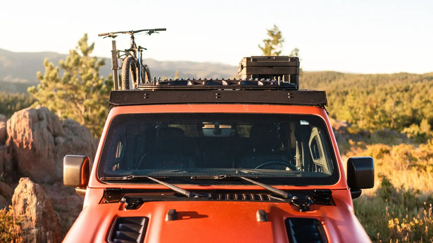 Front view of Jeep Gladiator JT with The Sunlight roof rack, showcasing mounted gear and rugged design in a mountain landscape.
