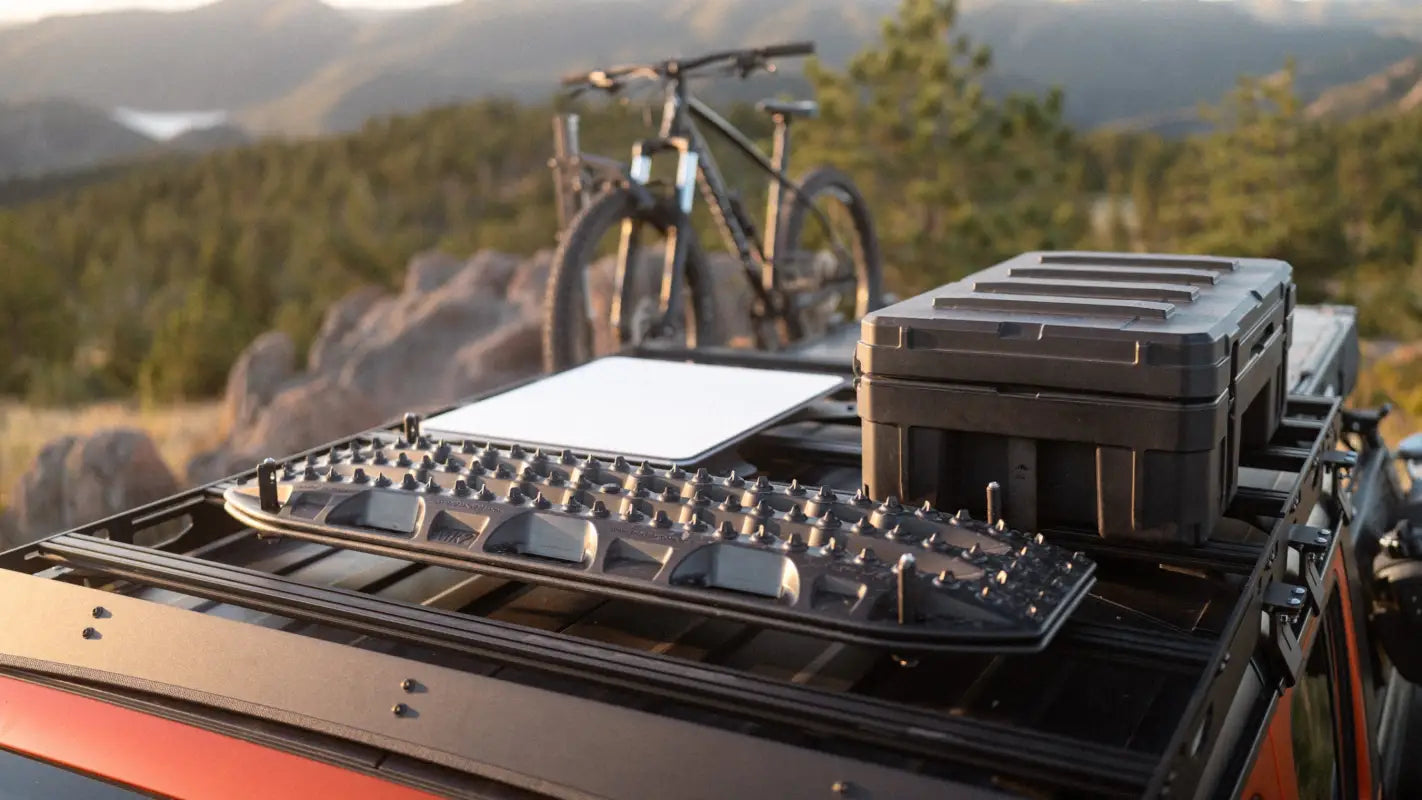 Top view of The Sunlight roof rack on Jeep Gladiator JT, loaded with recovery boards and a storage box, set against a mountain backdrop.