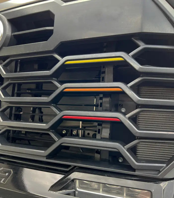 Close-up of TRD grille tri-color line inserts in yellow, orange, and red fitted on a Toyota Tundra or Sequoia grille.