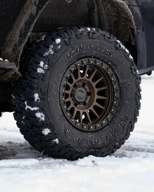 Mounted True Beadlock Ring for Hybrid Wheels V2 on an off-road vehicle tire in snowy terrain, emphasizing durability and performance.