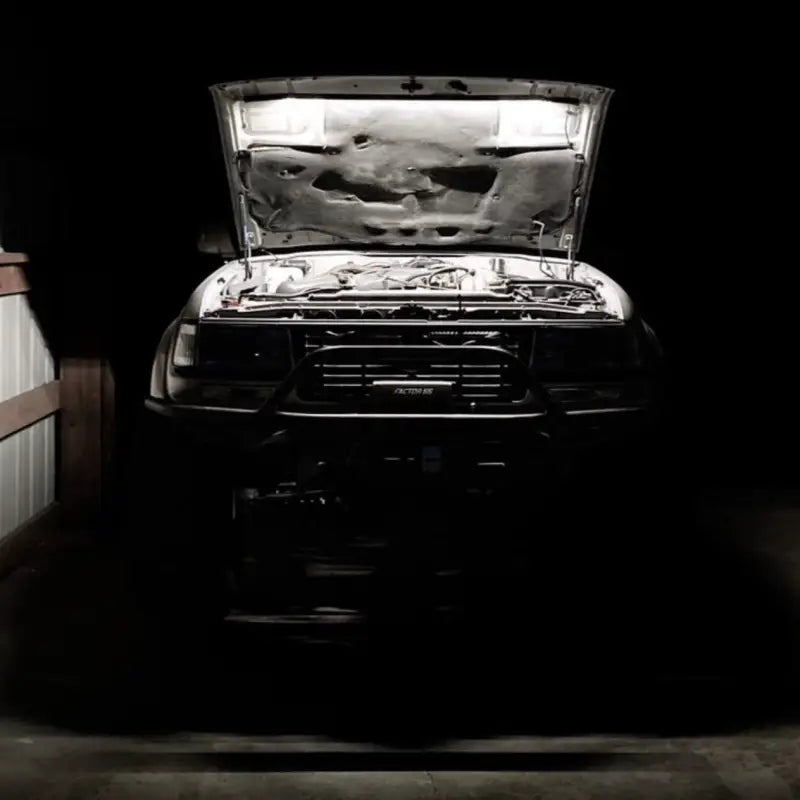 Toyota truck with its engine bay illuminated by the under hood LED light kit, providing bright lighting in a dark garage.