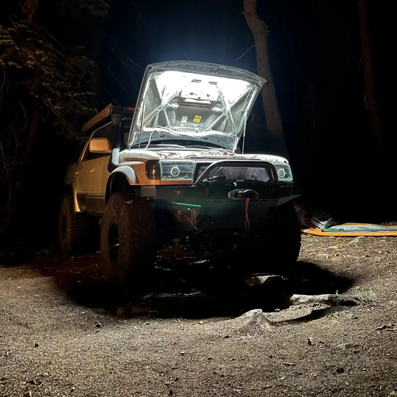 Off-road vehicle with an illuminated engine bay at night, equipped with a bright under hood LED light kit for outdoor use.