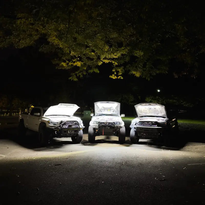 Three vehicles with hoods open at night, each equipped with under hood LED light kits, providing bright illumination for engine bays.