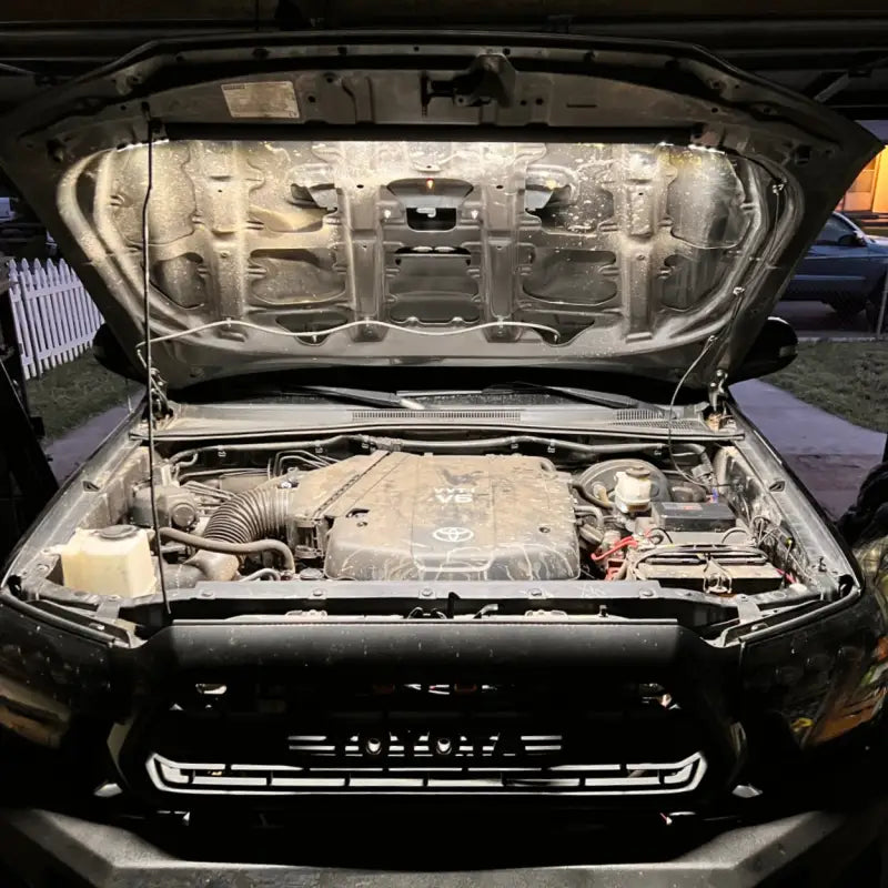 Toyota truck engine bay brightly lit by the under hood LED light kit, showcasing its 1,300-lumen output in a garage setting.