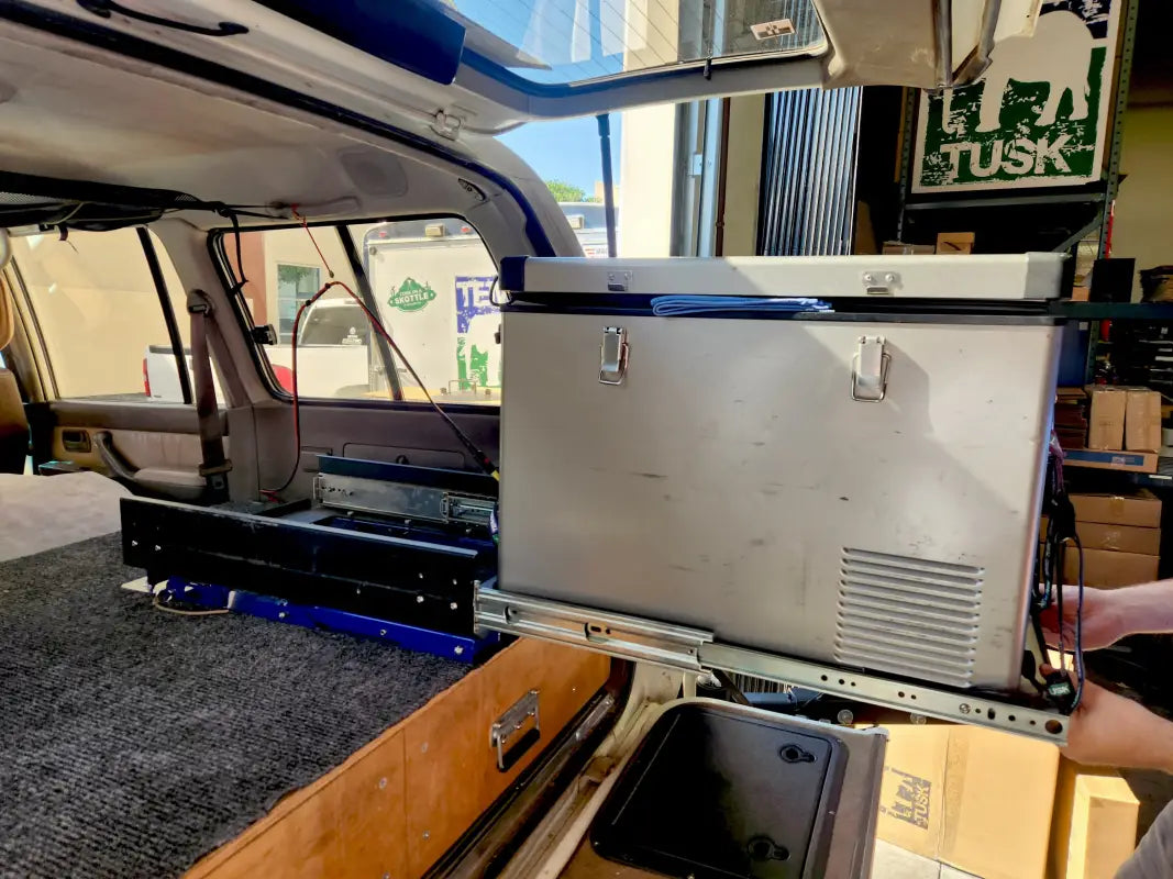 Universal Tilt Slide Adapter extended in a vehicle, showcasing its smooth sliding mechanism and compatibility with camping fridges.