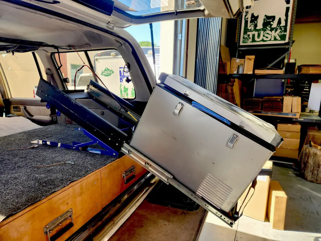 Universal Tilt Slide Adapter in use, tilting a fridge inside a vehicle for convenient access and enhanced camping functionality.