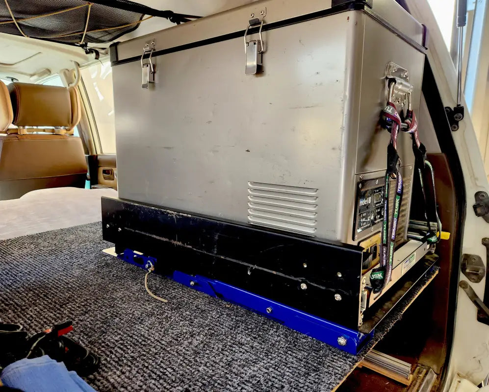 Fridge securely mounted on the Universal Tilt Slide Adapter in a vehicle, highlighting its sturdy design and camping compatibility.