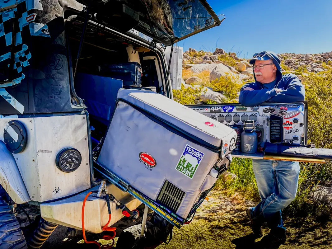 Universal Tilt Slide Adapter in use with a fridge on a rugged off-road vehicle, showcasing its 28° tilt functionality for camping convenience.