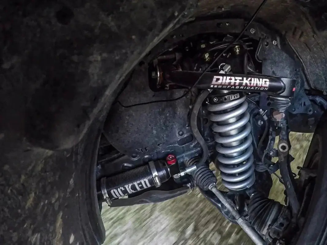 Close-up of 2010-2014 FJ Cruiser shock package with Dirt King coilovers and external reservoir during off-road use.