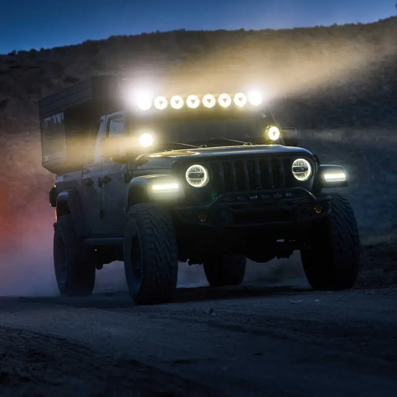 Black Jeep with the 50-inch Gravity Titan LED Light Bar illuminating a dusty off-road trail during nighttime.