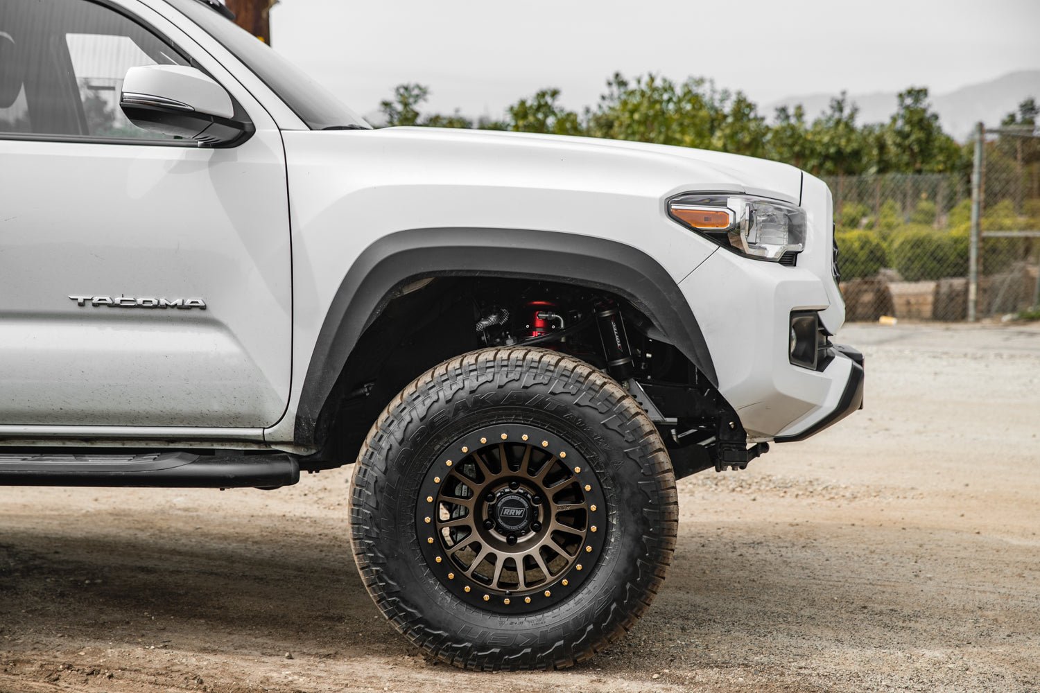 White truck equipped with hybrid wheels featuring black protection rings and gold bolts, designed for off-road performance.