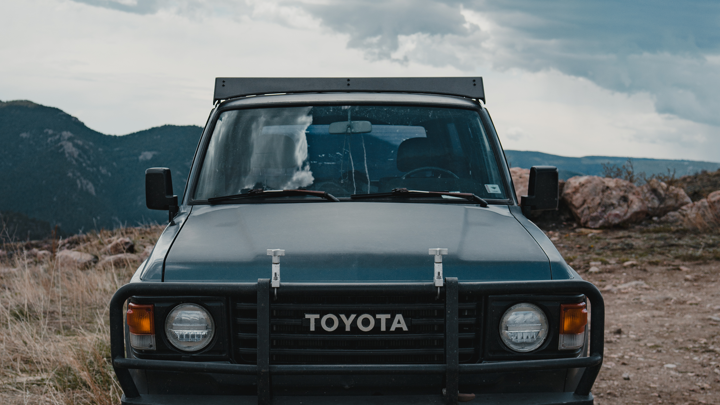 Front view of a Toyota Land Cruiser 60 Series with a rugged roof rack, ready for off-road adventures and gear transport.