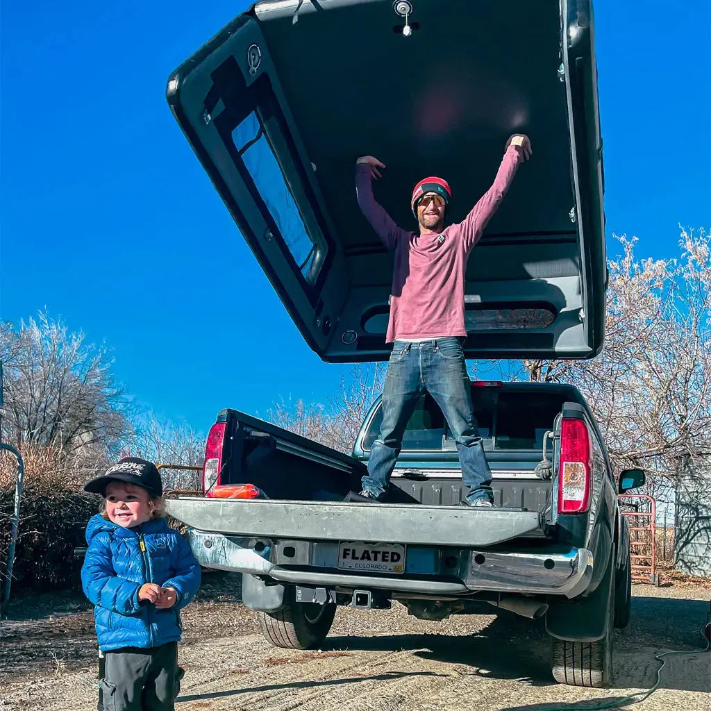 Man demonstrating the open setup of an inflatable truck cap on a truck bed, showcasing its spacious and lightweight design.