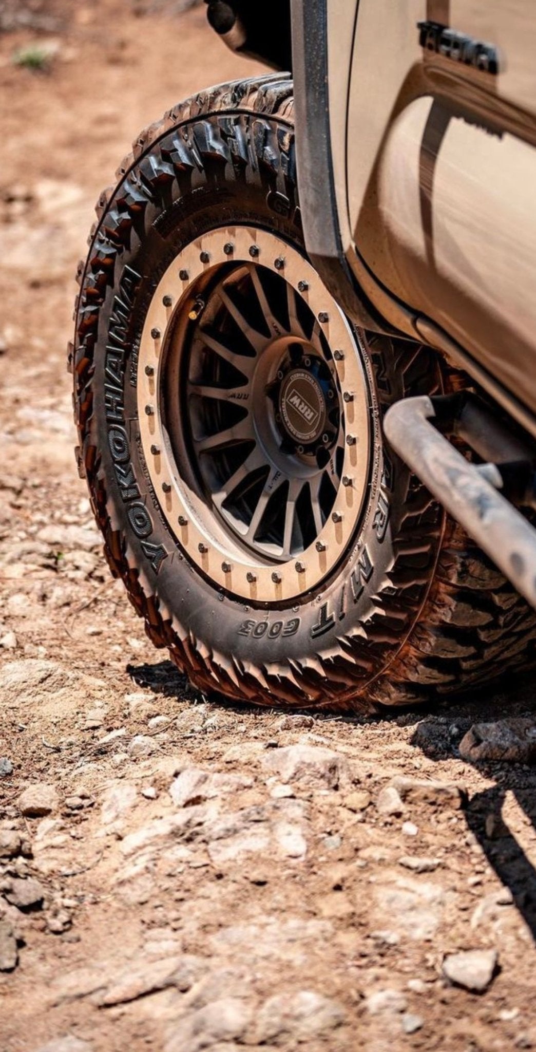 Hybrid wheel with a black protection ring installed on an off-road vehicle, highlighting rugged performance on rocky terrain.