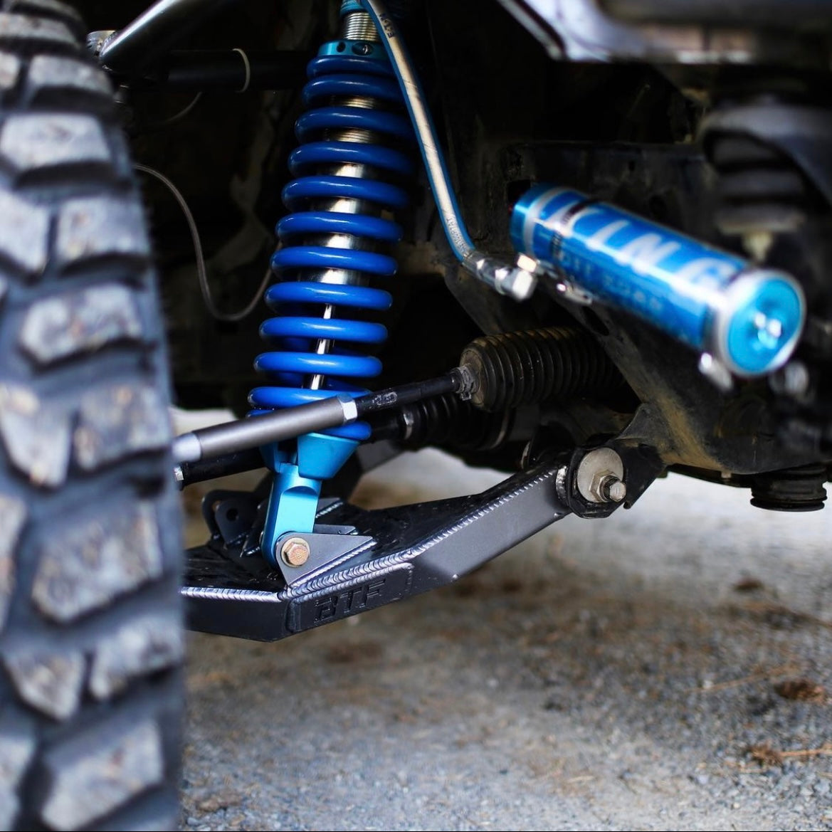 Detailed shot of GX460 long travel suspension with blue coil springs and upgraded components for off-road performance.