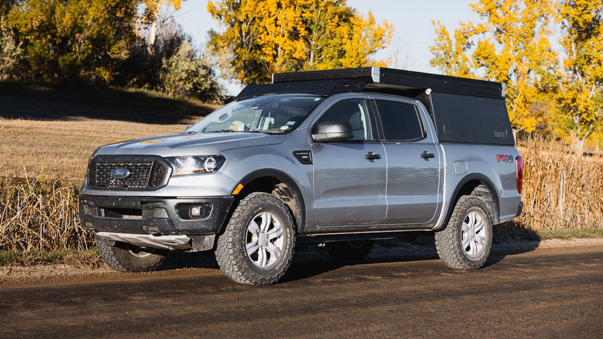 Ford Ranger with Stratus roof rack and GFC camper parked on a dirt road, ideal for outdoor enthusiasts needing extra storage.