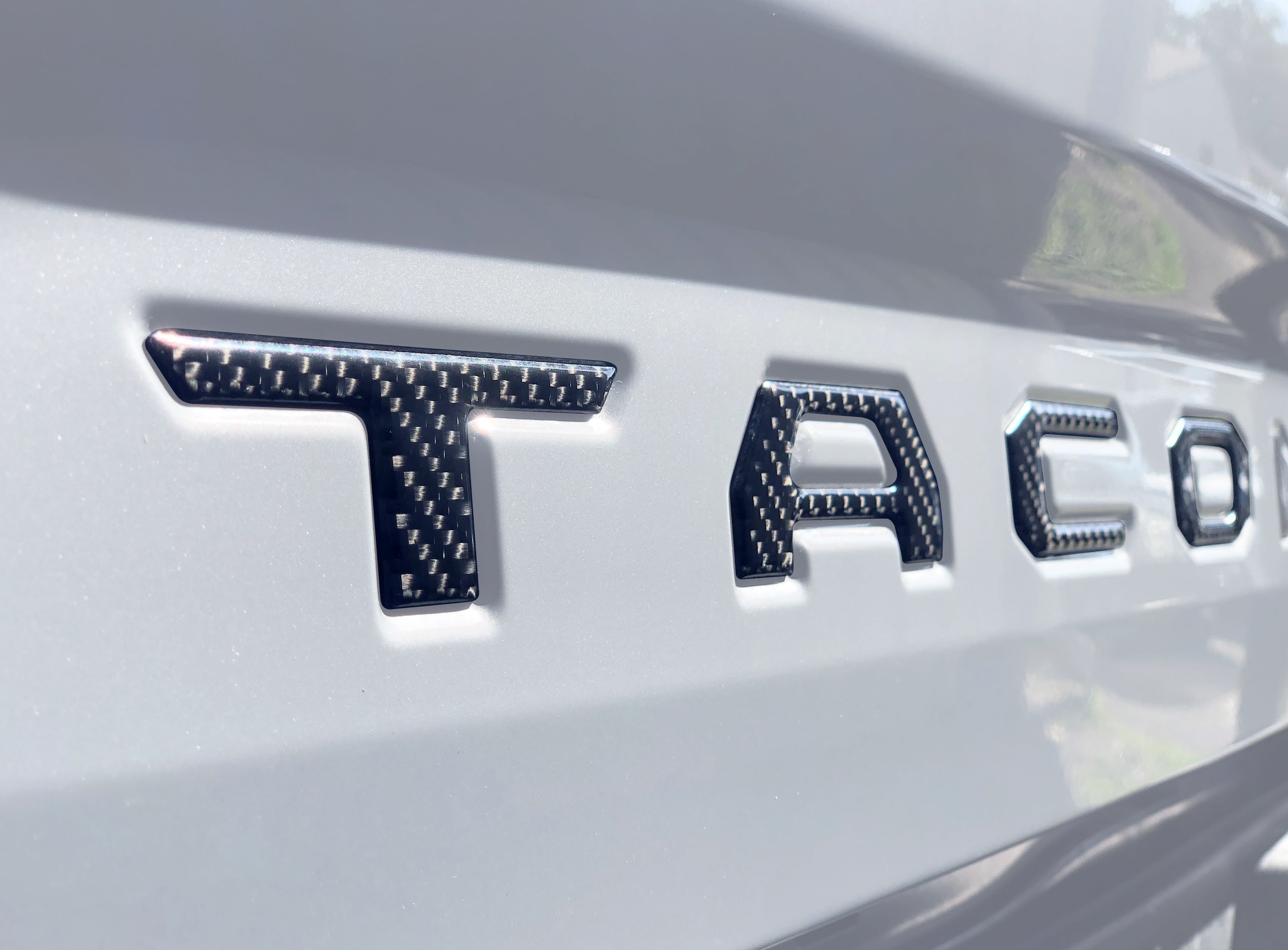 Close-up of carbon fiber tailgate letter inserts on a 2016-2023 Toyota Tacoma, showcasing a sleek and durable design.