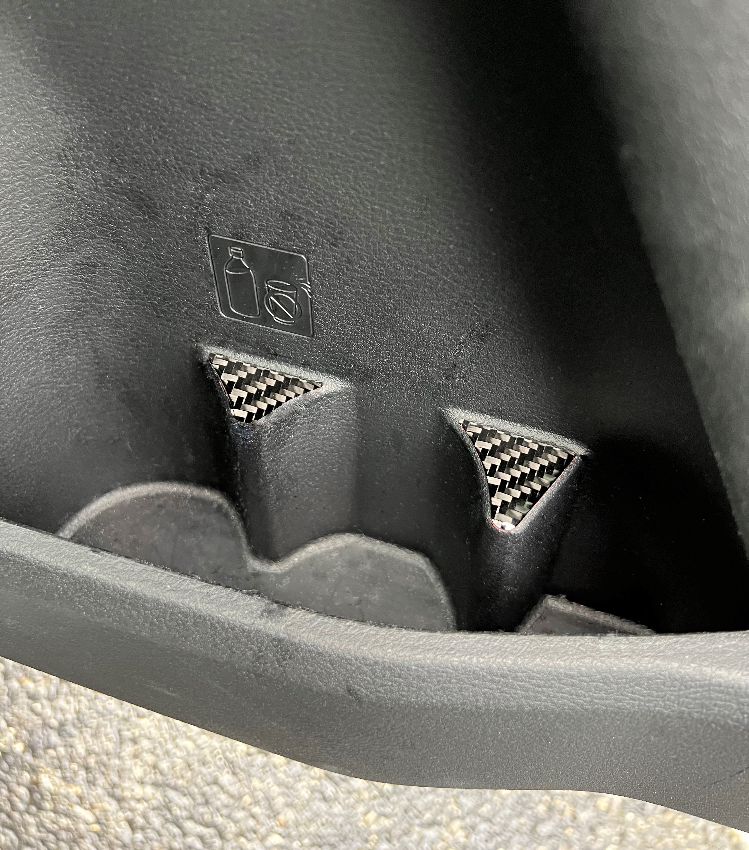 Detailed shot of carbon fiber door cupholder accent trim fitted in a 2016-2023 Toyota Tacoma, showcasing precise fit and premium finish.