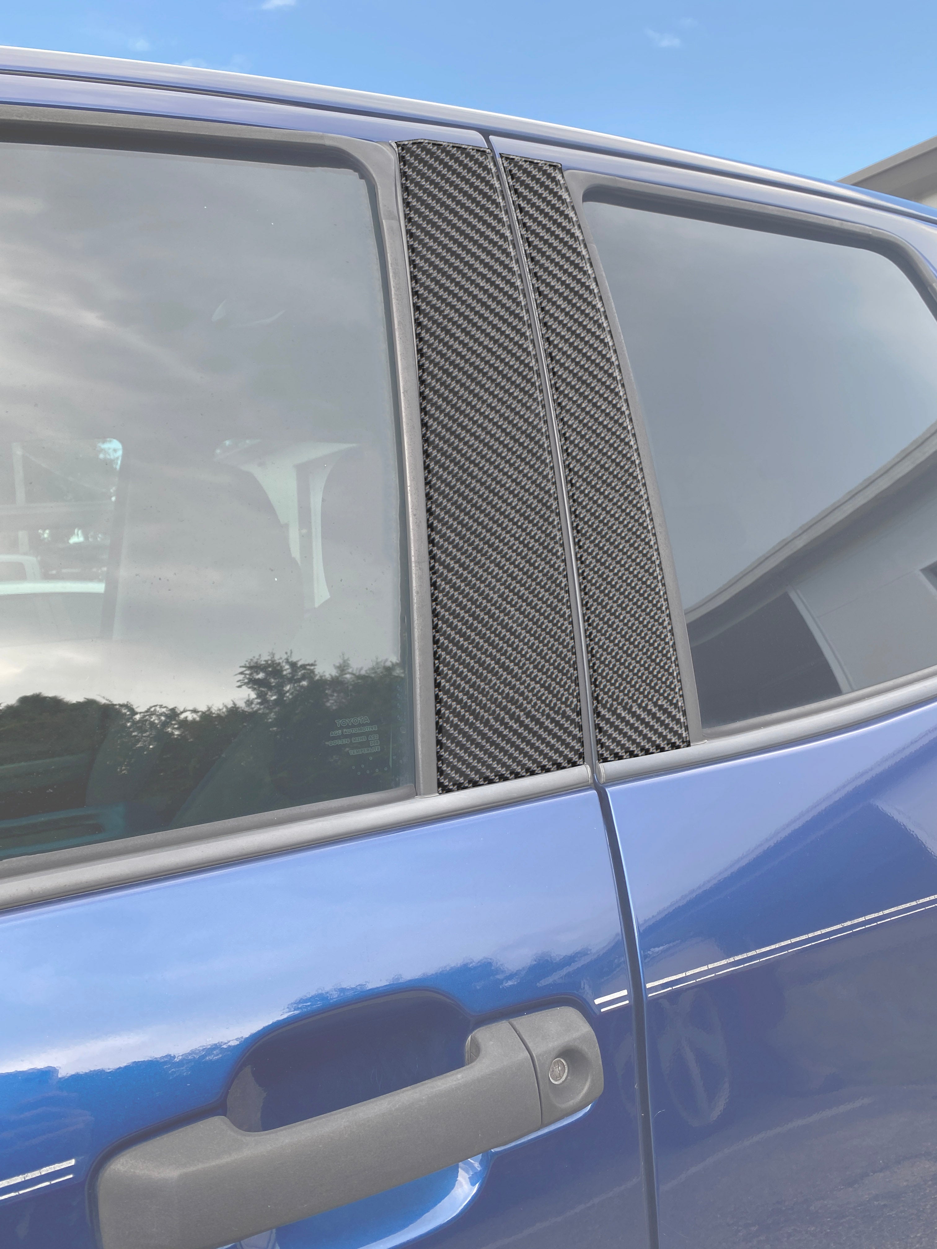 Carbon fiber-style door pillar accent trim installed on a blue Toyota Tundra, enhancing the vehicle's exterior appearance.