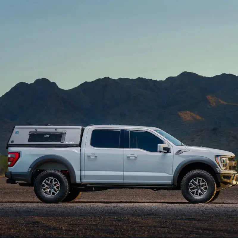 White truck with 5.5' Bed Air-Topper CAP installed, captured in a desert landscape, emphasizing its outdoor utility.